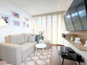 Ein modernes Wohnzimmer mit einer Couch, einem Couchtisch, einem Fernseher und Kunstwerken an der Wand.