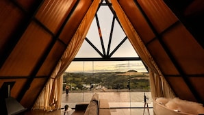 A modern interior with a large window offering a scenic view of hills and a distant town. - Chalé da Lagoa (Cordilheira Alta)