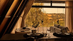 A modern kitchen with a dining area, a view of the countryside, and a large window. - Chalé da Lagoa (Cordilheira Alta)