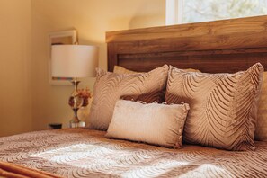 Ein Bett mit einer gemusterten Tagesdecke und mehreren Kissen.