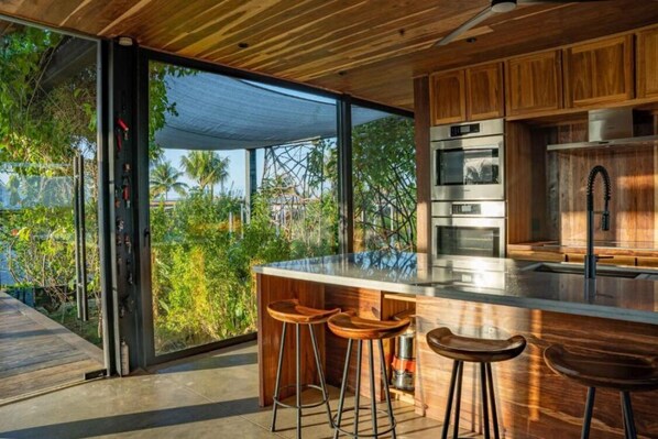 A modern kitchen with a large island, bar stools, and stainless steel appliances.