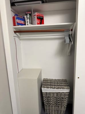 Un armario con estantes, una cesta de mimbre y cajas con artículos de primeros auxilios y limpieza.