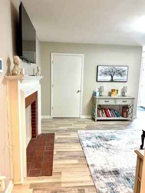 A living room with a fireplace, a bookshelf, and a door.