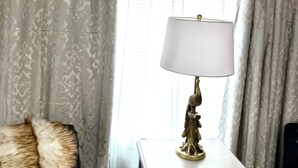 Et værelse med et mønstret gardin, en lampe på et hvidt natbord og en stol betrukket med pels.