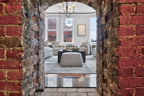 Ein modernes Wohnzimmer mit einem Ziegelbogen, der in eine Sitzecke mit Sofas und einem Couchtisch führt.