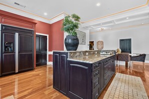 A modern kitchen with dark cabinetry, a large island, and a dining area with a chair. - Lexington "Pent Hous" Prime Location 4Bdrm, 6 Beds (Lexington)