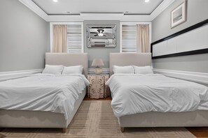 Ein Hotelzimmer mit zwei Betten, einem Nachttisch, einer Lampe und einem Deckenventilator.