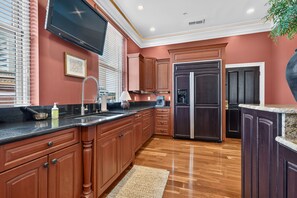 A kitchen with wooden cabinets, a stainless steel refrigerator, a built-in oven, and a large window with blinds. - Lexington "Pent Hous" Prime Location 4Bdrm, 6 Beds (Lexington)
