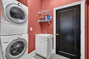 A laundry room with stacked washers and dryers, a small sink, and a door. - Lexington "Pent Hous" Prime Location 4Bdrm, 6 Beds (Lexington)