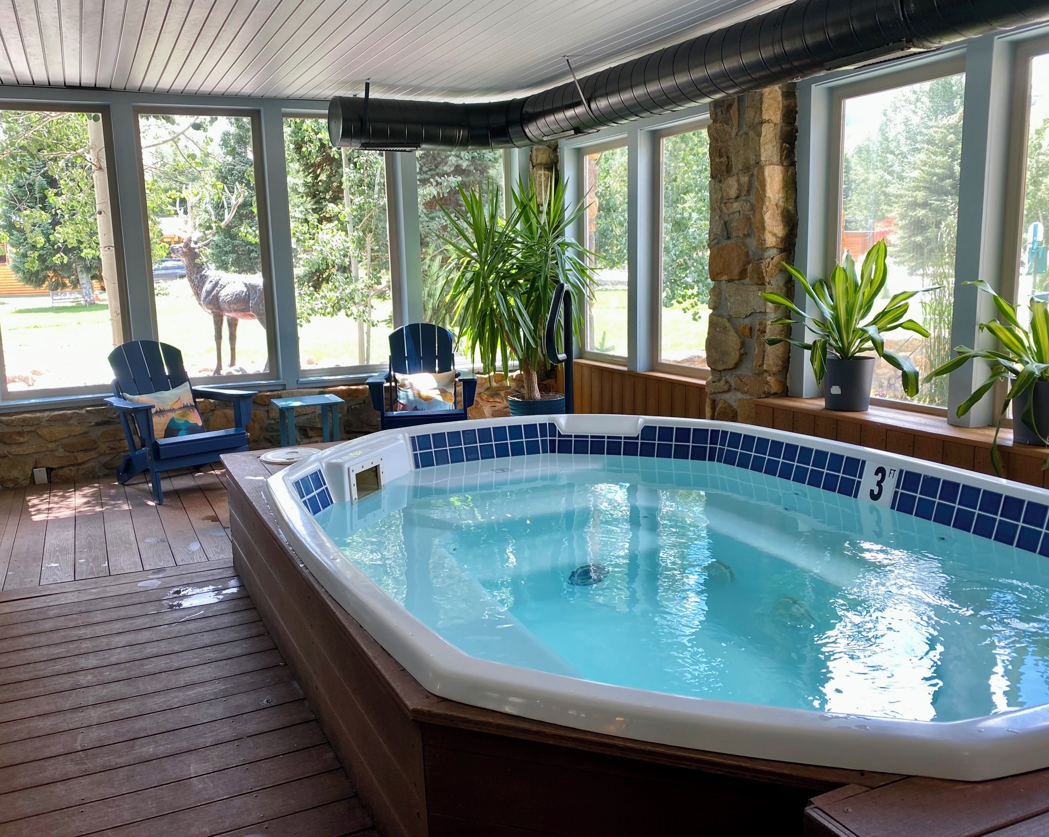 A hot tub with a 3 ft depth, surrounded by wooden decking, stone walls, and potted plants.