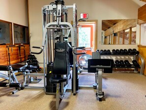A gym with a variety of exercise equipment, including a weight bench, dumbbells, and a squat rack.