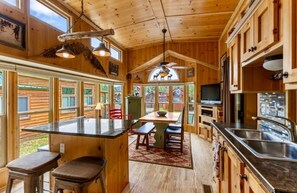 Interior de madera con área de cocina, mesa de comedor y asientos de bar.