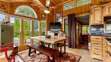 A wooden interior with a dining area, a television, and a kitchen.