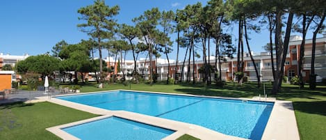 A rectangular swimming pool with a tiled edge, surrounded by well-maintained grass and trees.