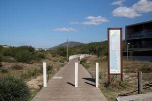 A wooden boardwalk leading to a building with a map sign. - Casa Suave Mar (Marinhas)