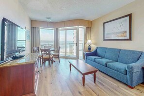 Ein Hotelzimmer mit Balkon, Fernseher, Sofa, Couchtisch und Essbereich.