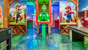 A room with two large Mario statues, a green-lit central display, and a table with a Mario-themed design. - Luxury 8BR Themed Villa With Private Pool (Clermont)