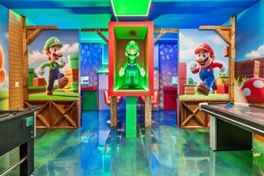 A room with two large Mario statues, a green-lit central display, and a table with a Mario-themed design. - Luxury 8BR Themed Villa With Private Pool (Clermont)