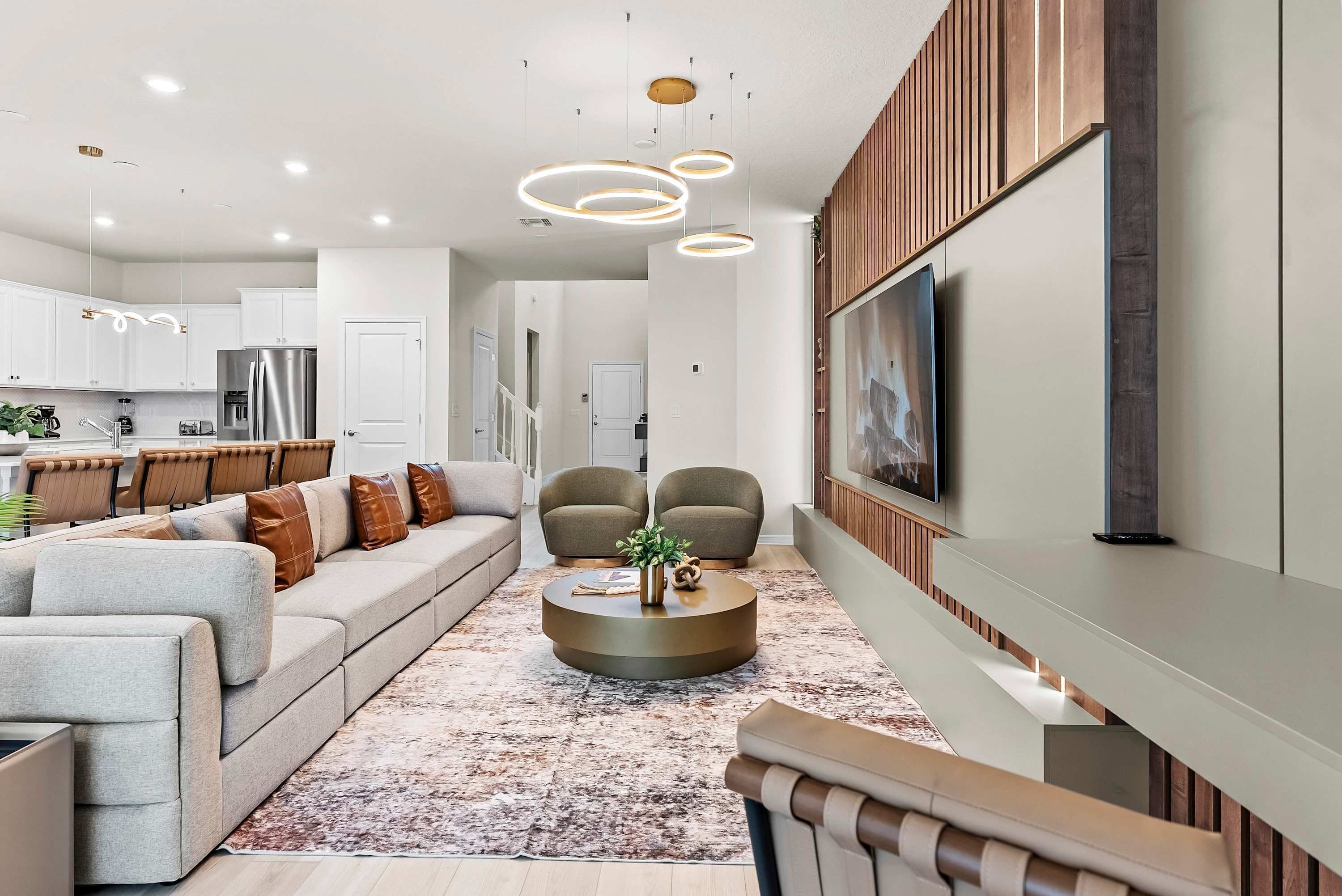 A modern living room with a sofa, chairs, a coffee table, and a TV mounted on the wall.