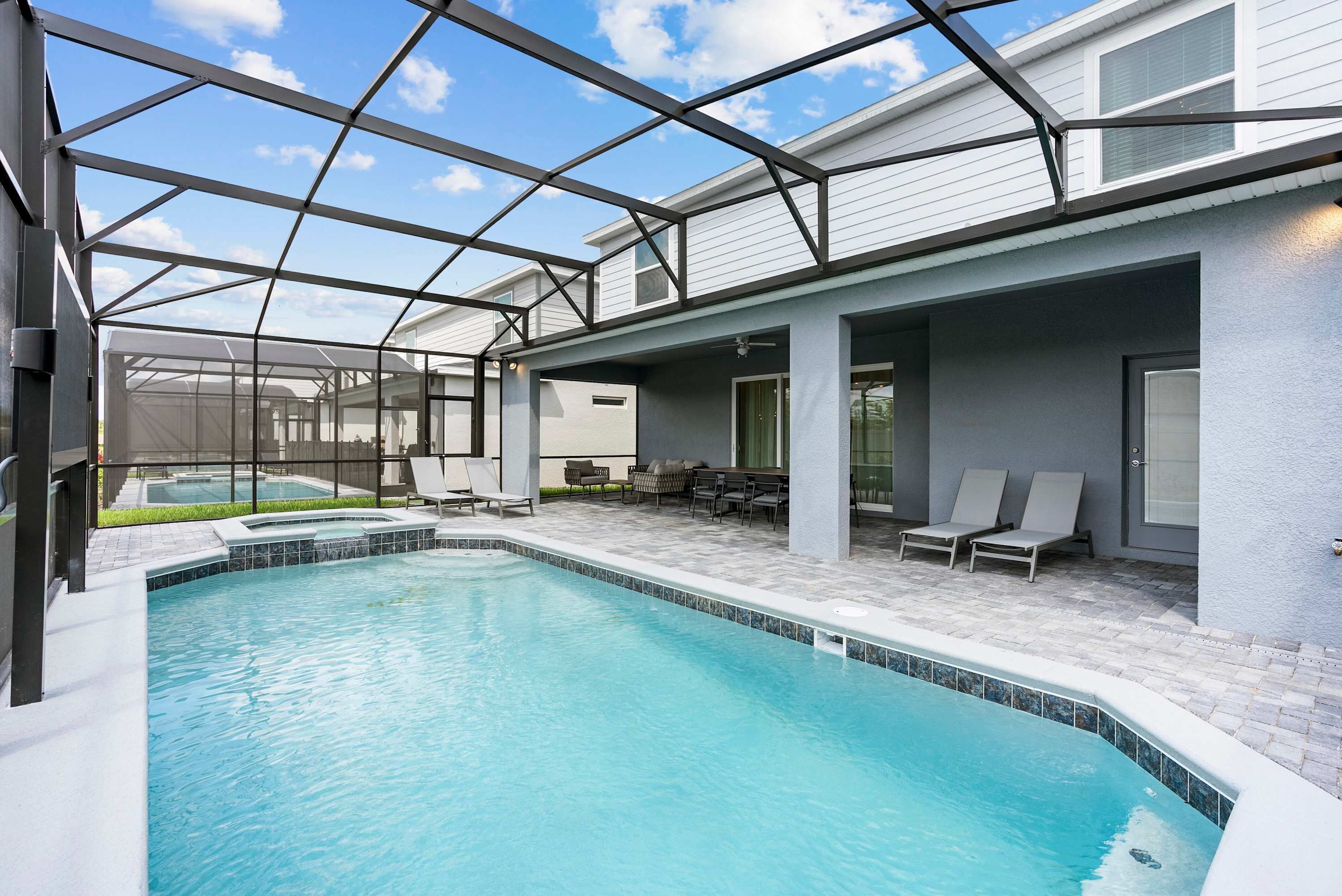 Et poolområde med en glasindhegnet terrasse, liggestole og et separat poolområde.