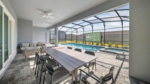 A covered outdoor area with a pool, seating, and a large screen displaying the NFL logo. - Luxury 8BR Themed Villa With Private Pool (Clermont)