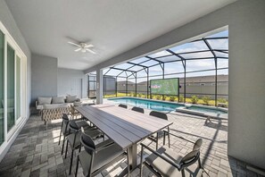 A covered outdoor area with a pool, seating, and a large screen displaying the NFL logo. - Luxury 8BR Themed Villa With Private Pool (Clermont)