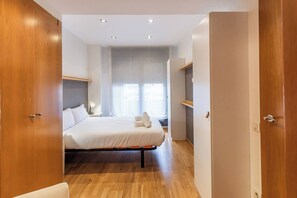 A modern hotel room with a bed, wooden wardrobe, and a window with curtains. - 6CBADR1141 Apartment near the beach &swimming pool (Barcelona)
