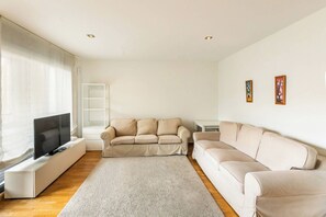 A living room with a TV, two sofas, a white rug, and a window with curtains. - 6CBADR1141 Apartment near the beach &swimming pool (Barcelona)