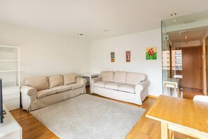 Ein Wohnzimmer mit zwei Sofas, einem Couchtisch und einem Fernseher-Schrank.
