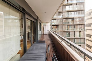A narrow balcony with a wooden floor, glass doors, and a view of adjacent buildings. - 6CBADR1141 Apartment near the beach &swimming pool (Barcelona)