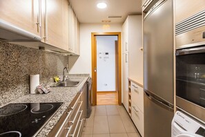 A compact kitchen with granite countertops, stainless steel appliances, and wooden cabinets. - 6CBADR1141 Apartment near the beach &swimming pool (Barcelona)