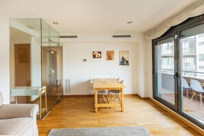 A modern living room with a wooden dining table, a glass partition, and a large sliding glass door leading to an outdoor area. - 6CBADR1141 Apartment near the beach &swimming pool (Barcelona)