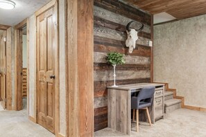 Ein Zimmer mit einem Holztisch, einem Stuhl, einer Pflanze und einem an der Wand befestigten Schädel.
