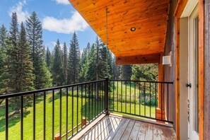 A wooden balcony with a metal railing overlooking a forested area. - Aspen Pond Retreat | 7 Mi to YNP | Private Pond (West Yellowstone)