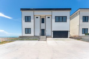 A modern two-story building with a flat roof, a central entrance with a door, and a garage on the right side. - 19 Spacious Bay (Port Isabel)