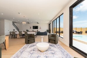 Ein geräumiges Wohnzimmer mit großem Fenster, Essbereich und Blick zum Pool.