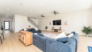 A modern living room with a sofa set, wooden cabinet, and a flat-screen TV. - NEW Luxury 5,500 SF Waterfront Home w/ Pool, Sleeps 28 (Port Isabel)