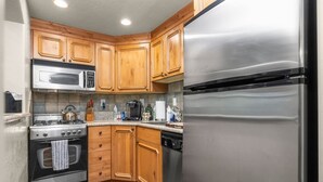 A compact kitchen with wooden cabinets, a stainless steel refrigerator, a microwave, a stove, and a dishwasher. - Swiss Mountain Escape | Pool | Hot Tub | Tennis (Midway)