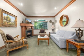 A living room with a fireplace, a sofa, a chair, and a coffee table. - Swiss Mountain Escape | Pool | Hot Tub | Tennis (Midway)