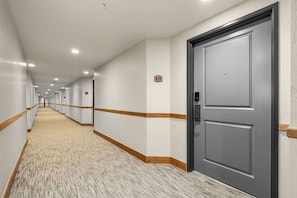 A hotel corridor with carpeted floors, wooden trim, and a closed door with a keypad lock. - Swiss Mountain Escape | Pool | Hot Tub | Tennis (Midway)
