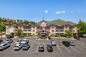 A multi-story hotel with a central entrance, parking lot, and mountainous backdrop. - Swiss Mountain Escape | Pool | Hot Tub | Tennis (Midway)