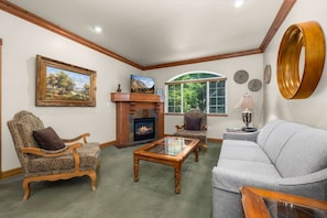 A living room with a fireplace, a sofa, a chair, and a coffee table. - Swiss Mountain Escape | Pool | Hot Tub | Tennis (Midway)