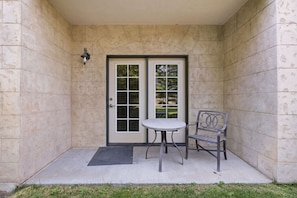 A covered patio area with a door, a table, and a chair. - Swiss Mountain Escape | Pool | Hot Tub | Tennis (Midway)