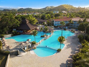 Un resort con una amplia piscina, sillas de descanso y palmeras.