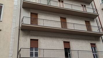 Un edificio a più piani con balconi, un portone di garage e graffiti.