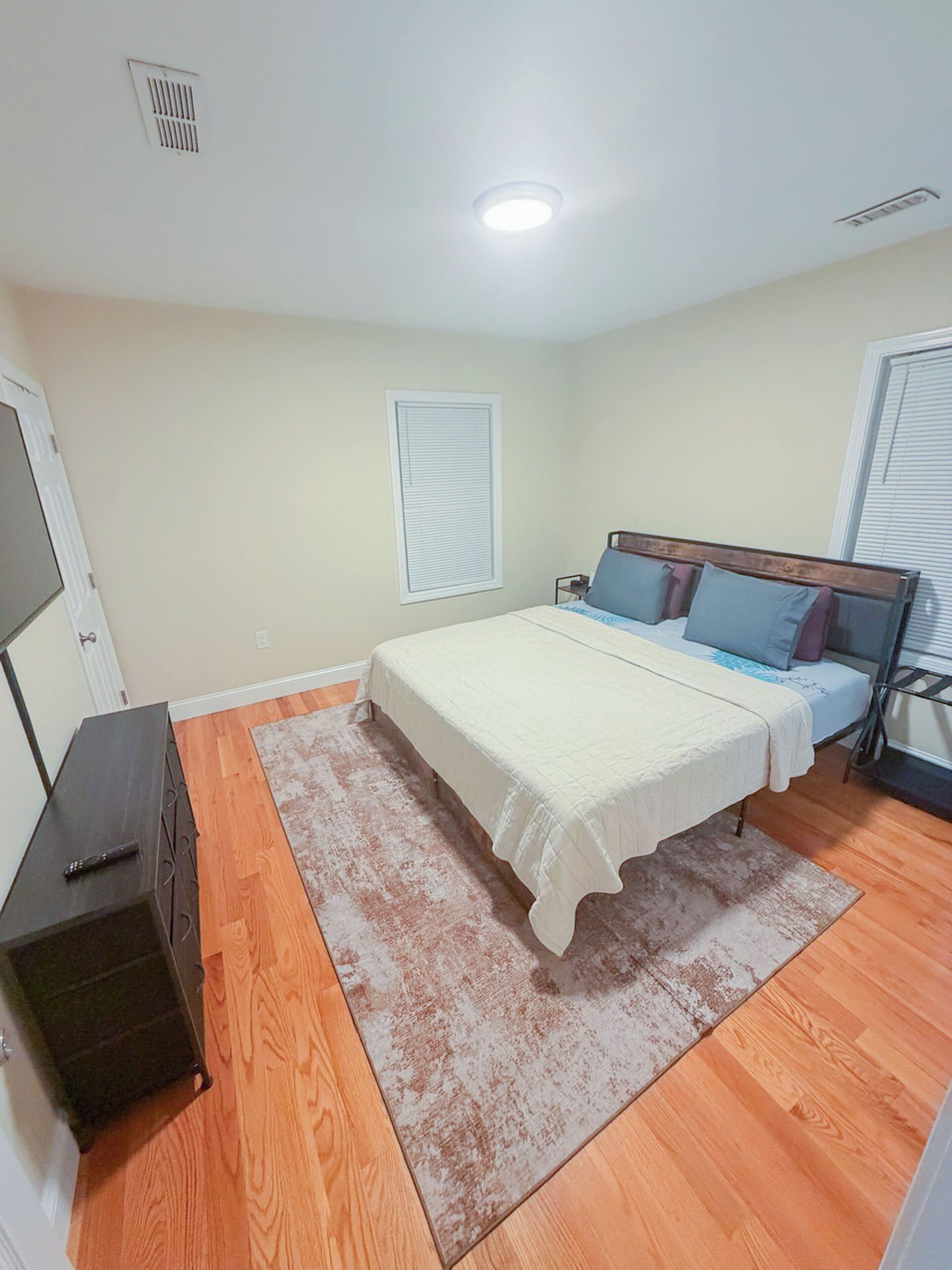 A bedroom with two beds, a dresser, and a window with blinds.