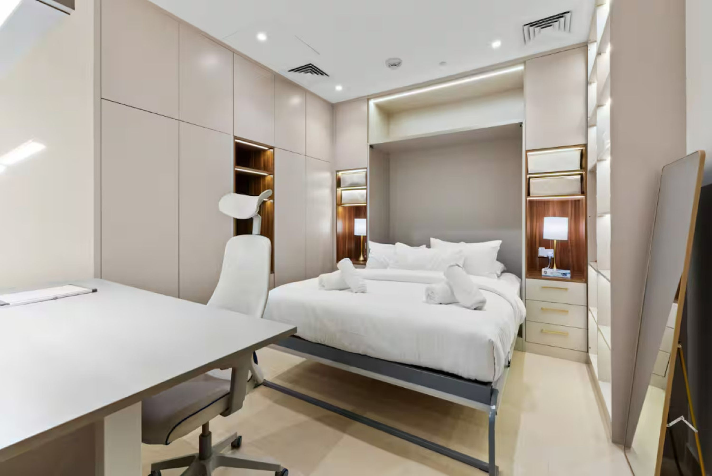 Ein modernes Hotelzimmer mit Bett, Nachttischen, einem Schreibtisch und einem Sessel.