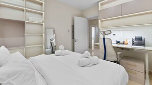 Ein Hotelzimmer mit Bett, Schreibtisch und Stuhl. Auf dem Bett liegen Handtücher.