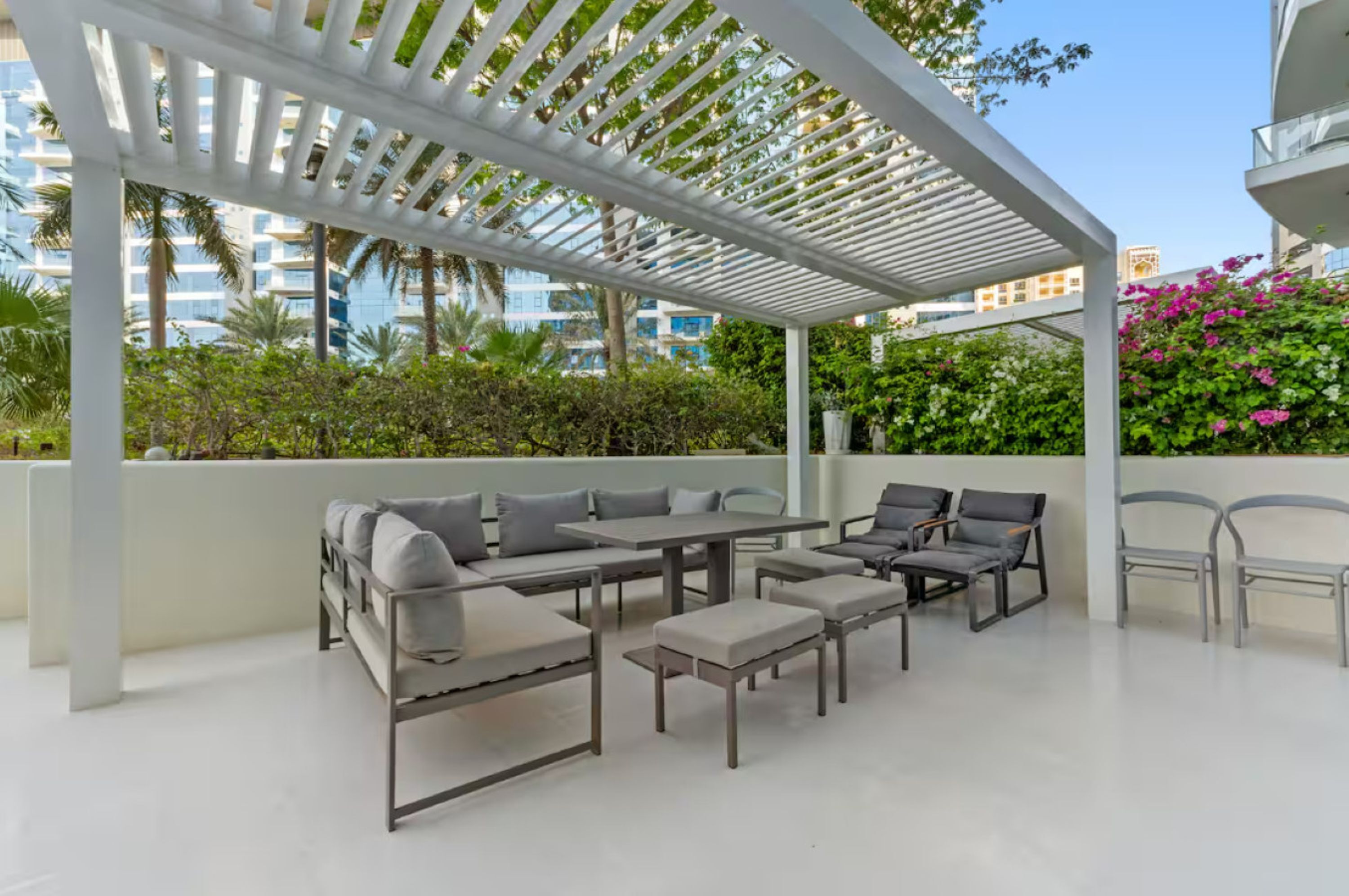 An outdoor patio with a pergola, seating area, and a view of the cityscape.
