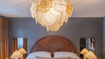 A hotel room with a large bed, two bedside lamps, a mirror, and a chandelier.